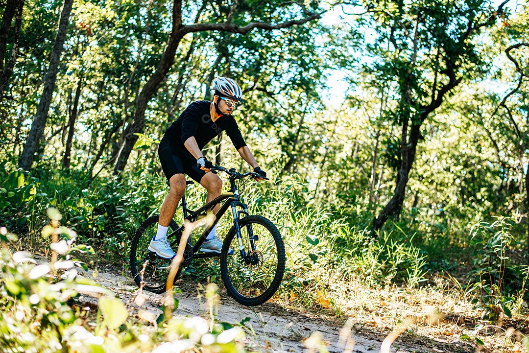 O homem andando de bicicleta em um caminho de montanha.