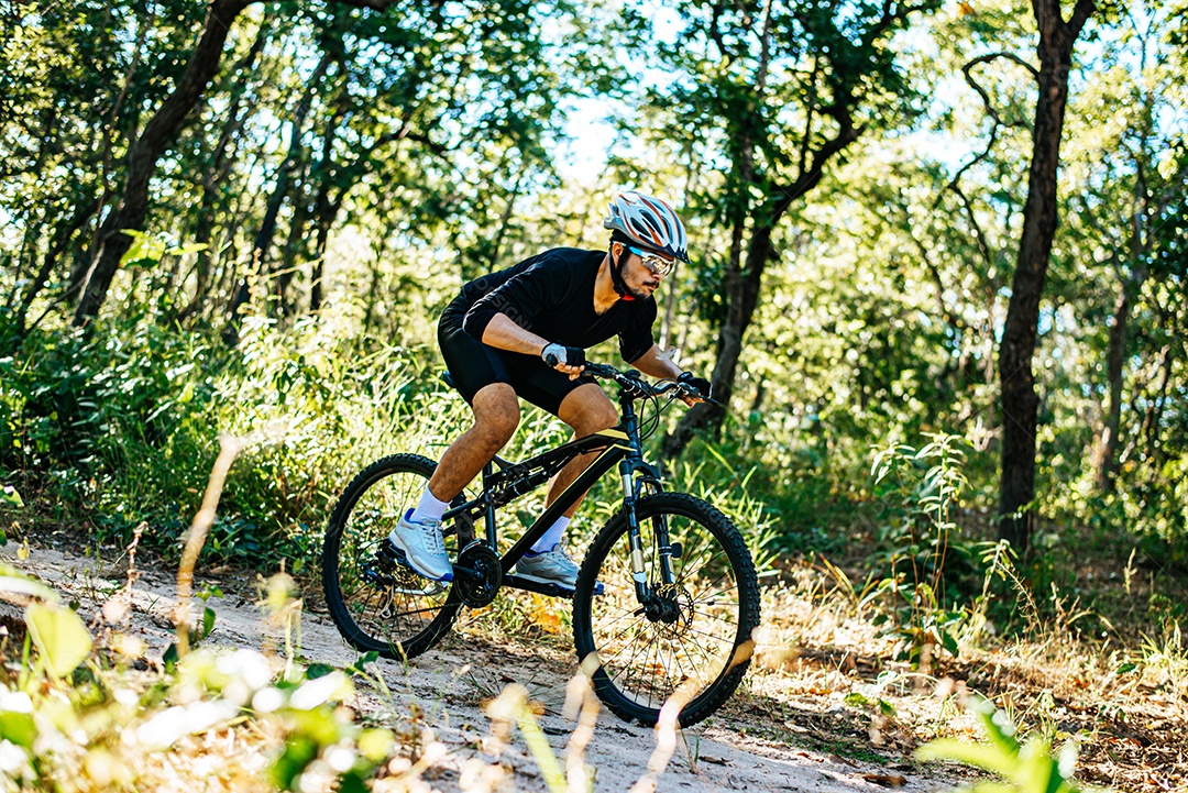 O homem andando de bicicleta em um caminho de montanha.