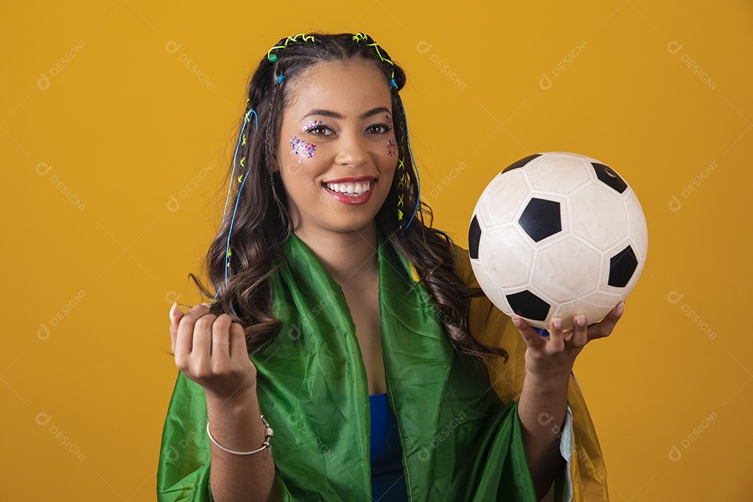 Linda mulher jovem com a bandeira do brasil nas suas costas sobre fundo amarelo