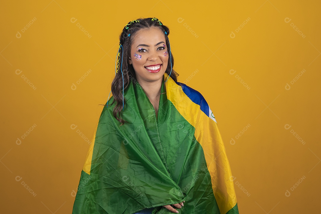 Beautiful young woman with the brazil flag behind her back on a yellow background