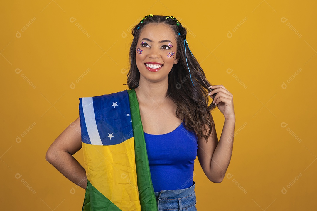Linda mulher jovem com a bandeira do brasil nas suas costas sobre fundo amarelo
