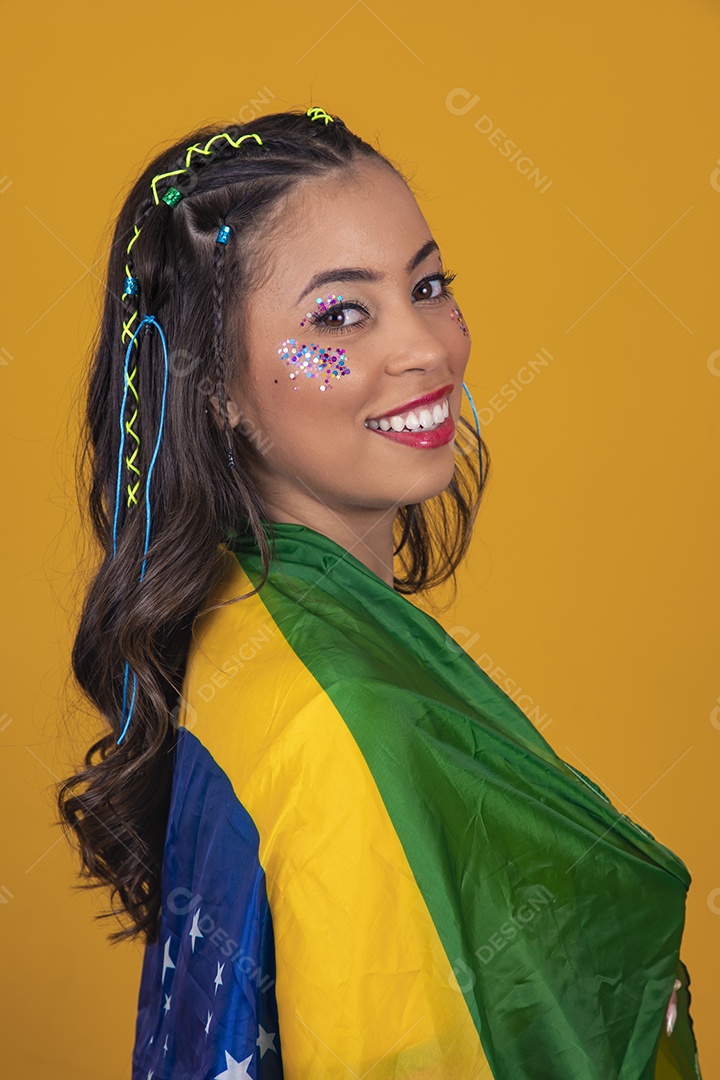 Linda mulher jovem com a bandeira do brasil nas suas costas sobre fundo amarelo