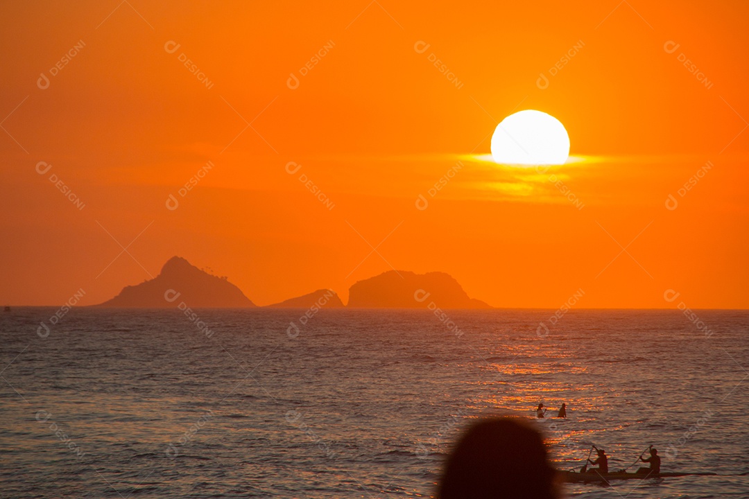 silhueta de pessoas assistindo o pôr do sol na praia do arpoador no rio de janeiro, brasil.