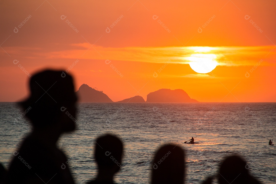 silhueta de pessoas assistindo o pôr do sol na praia do arpoador no rio de janeiro, brasil.