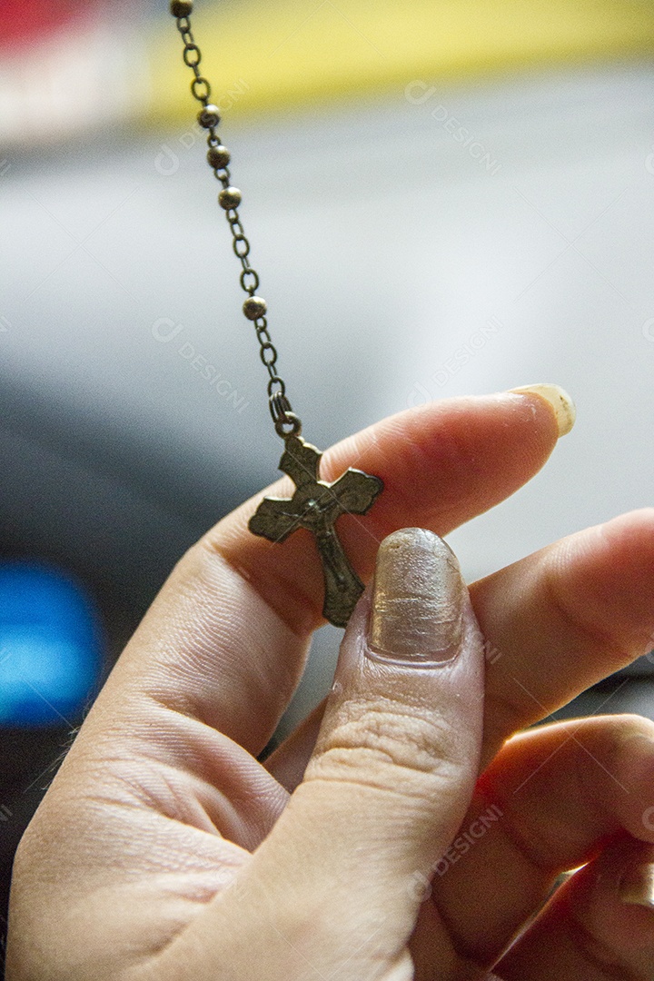 mão feminina com um terço de cristo