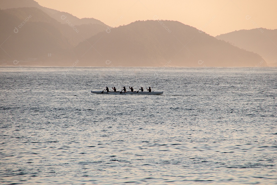 silhueta de pessoas remando uma canoa havaiana na praia de Copacabana, no Rio de Janeiro, Brasil.