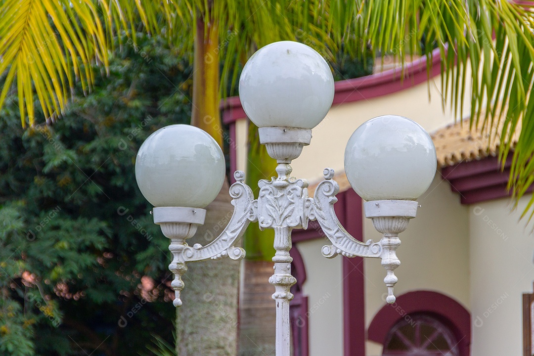 Candelabro velho na frente de uma casa velha com parede branca e vinho no Brasil.