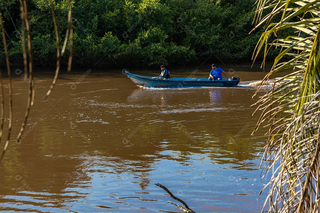 Mato grosso do sul / brasil - pescador, pescando no rio aquidauana no pantanal enquanto um barco com mais pescadores se aproxima