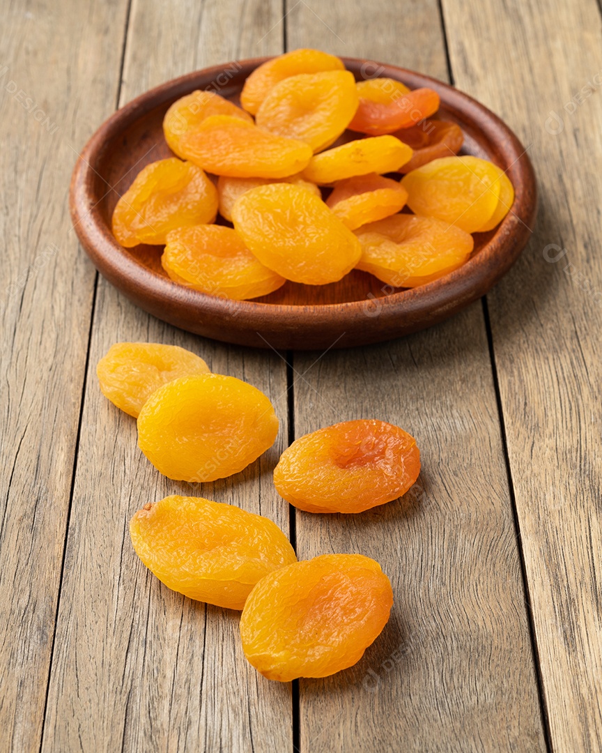 Damascos secos em um prato sobre a mesa de madeira.