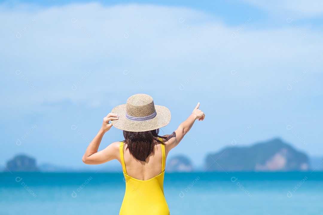 Turista de mulher de maiô amarelo e chapéu, feliz viajante tomando sol na praia do paraíso nas ilhas. destino, desejo de viajar, verão tropical, férias e conceito de férias