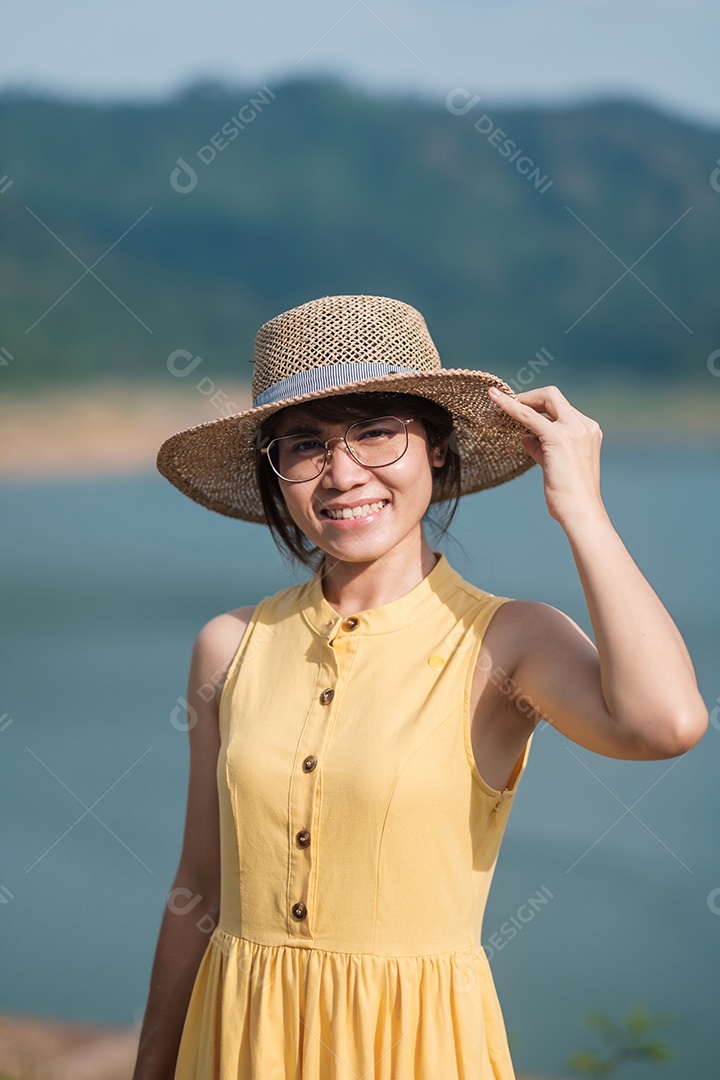 Mulher asiática de vestido amarelo e chapéu viajando ao ar livre, viajante feliz olhando para a represa de Khun dan Prakarnchon. Marco e popular para atrações turísticas em Nakhon Nayok, Tailândia