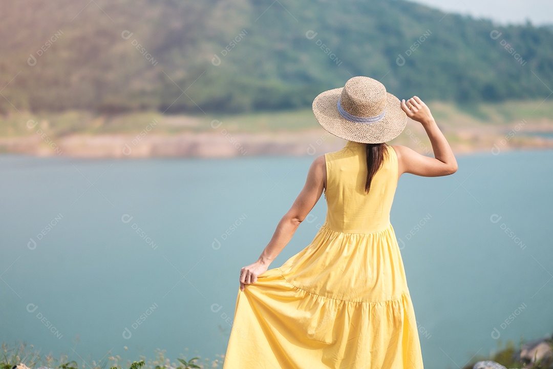 Mulher asiática de vestido amarelo e chapéu viajando ao ar livre, viajante feliz olhando para a represa de Khun dan Prakarnchon. Marco e popular para atrações turísticas em Nakhon Nayok, Tailândia