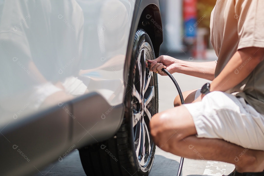 Motorista de homem inflando os pneus do veículo, removendo a tampa de nitrogênio da válvula do pneu para verificar a pressão do ar e encher o ar na roda do carro no posto de gasolina. self-service, manutenção e segurança