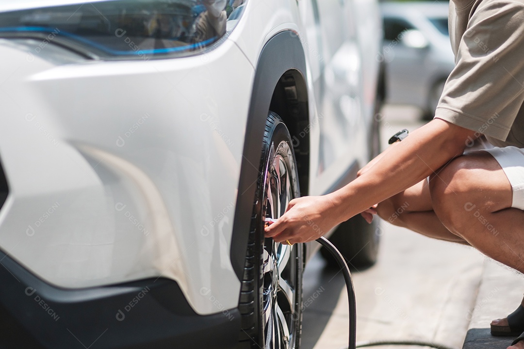 Motorista de homem inflando os pneus do veículo, removendo a tampa de nitrogênio da válvula do pneu para verificar a pressão do ar e encher o ar na roda do carro no posto de gasolina. self-service, manutenção e segurança