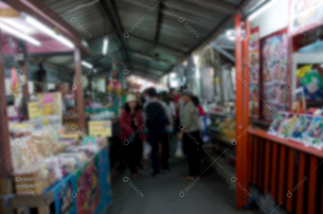 Imagem borrada de pessoas andando no mercado de dia.