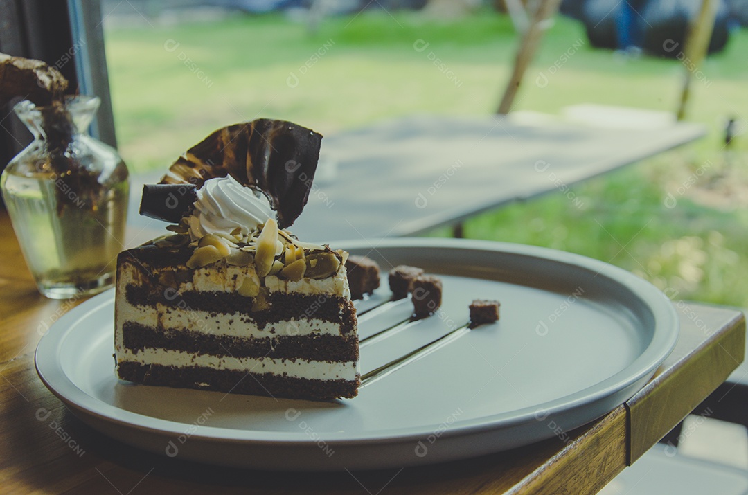 Bolo de chocolate no prato perto da janela do café, tom vintage.