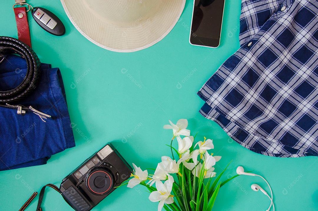 Acessórios de viajante. Chapéu, câmera, roupas e flores e telefone no fundo verde.