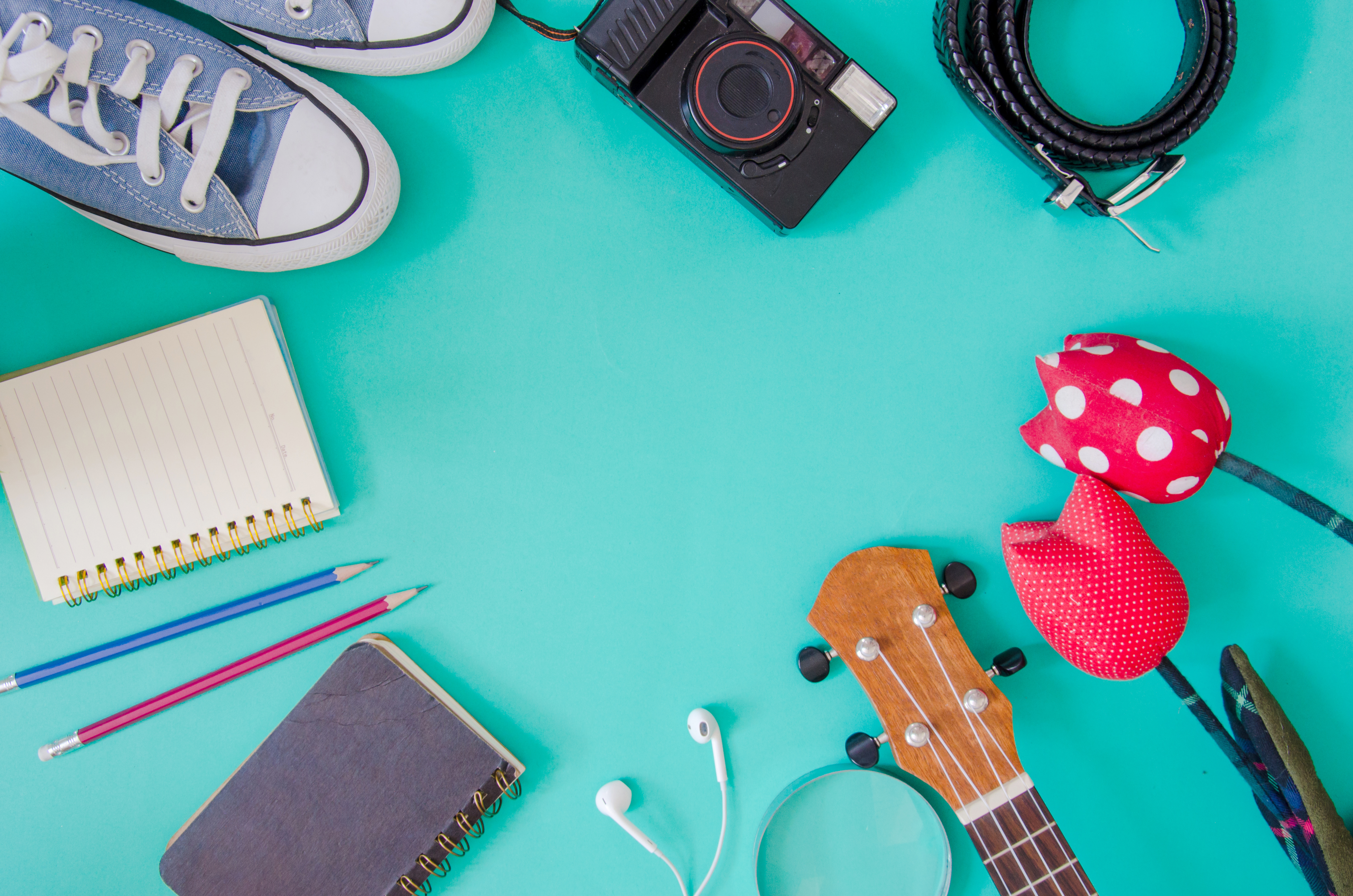 Acessórios de viajante. Sapatos, ukulele, lápis e cadernos e telefone no fundo verde.