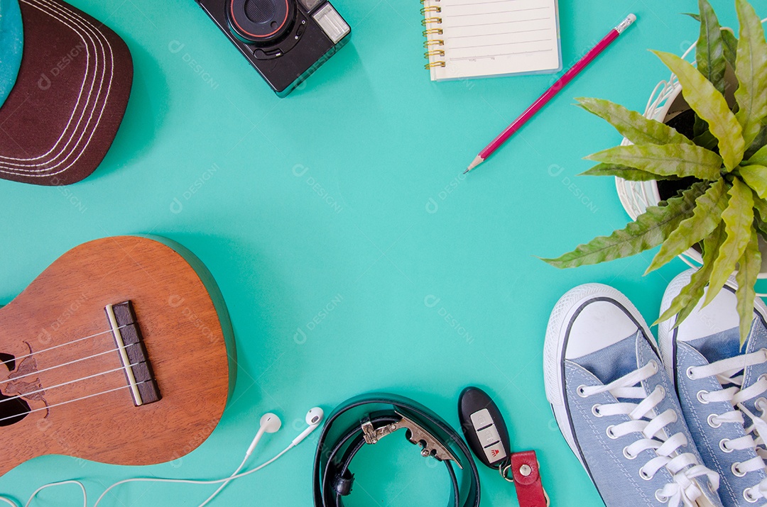 Acessórios de viajante. Sapatos, ukulele, lápis e cadernos e telefone no fundo verde.