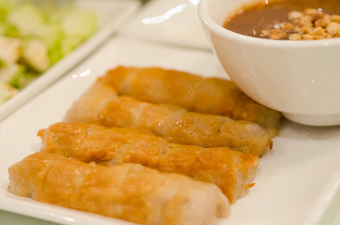 Comida vietnamita servida com molhos e legumes.