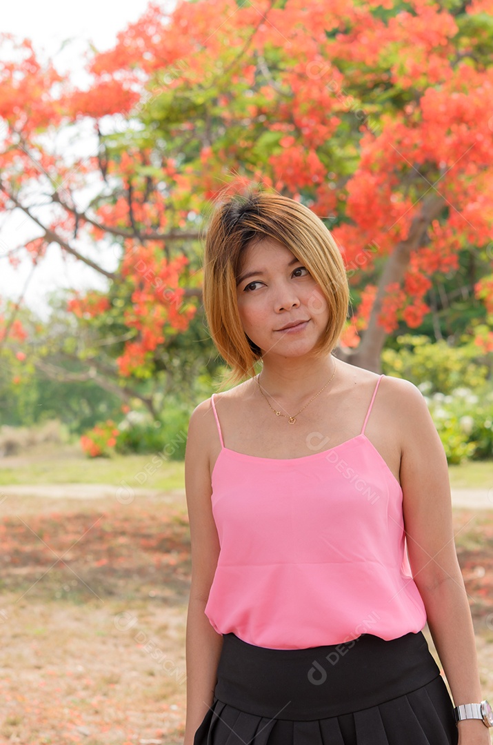 Camisa rosa feminina em pé no jardim.