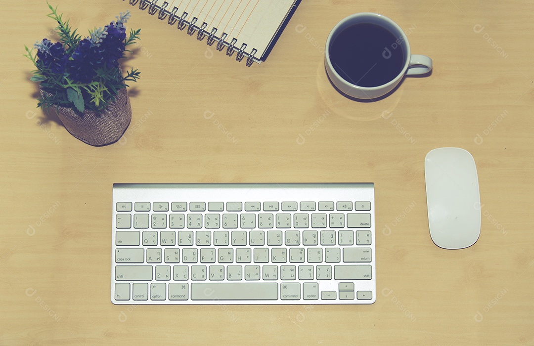 Mesa de escritório com bloco de notas, computador e xícara de café.
