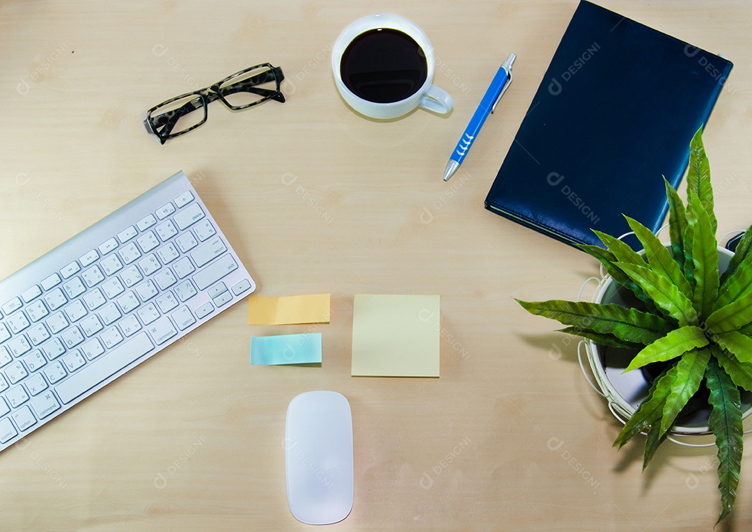 Material de escritório e xícara de café na mesa de madeira.