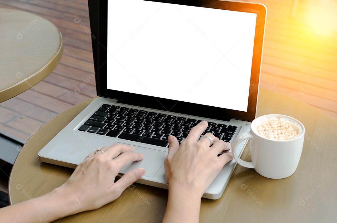 Computador portátil e xícara de café na mesa.