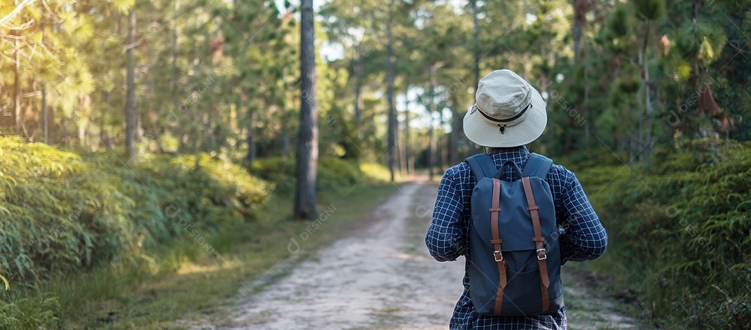 Jovem com mochila e chapéu caminhando nas montanhas durante o verão