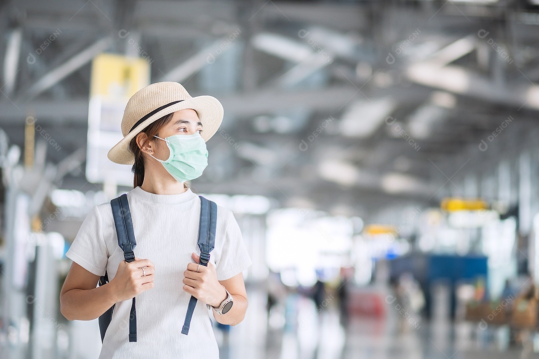 Mulher adulta jovem usando máscara cirúrgica no terminal do aeroporto