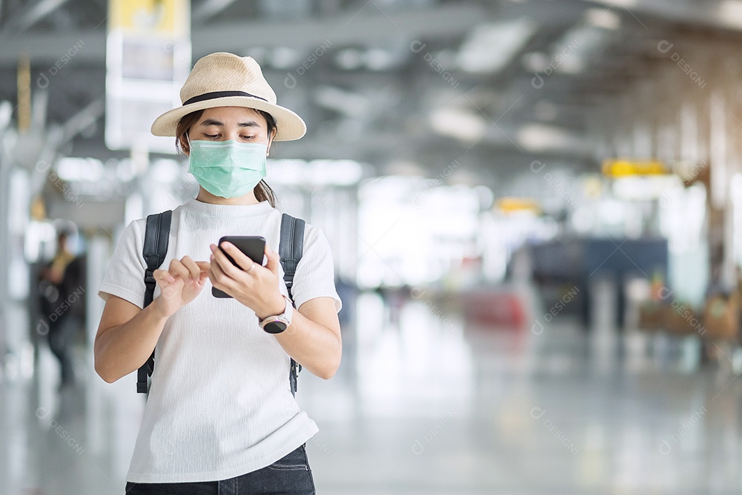 Jovem mulher usando máscara facial e usando smartphone