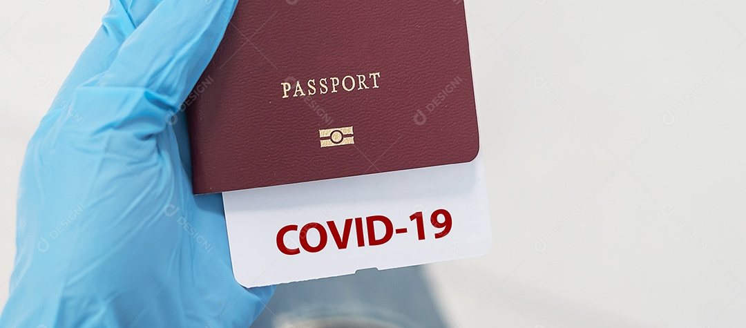Mão usando luva nitrílica segurando passaporte com nota COVID-19,
