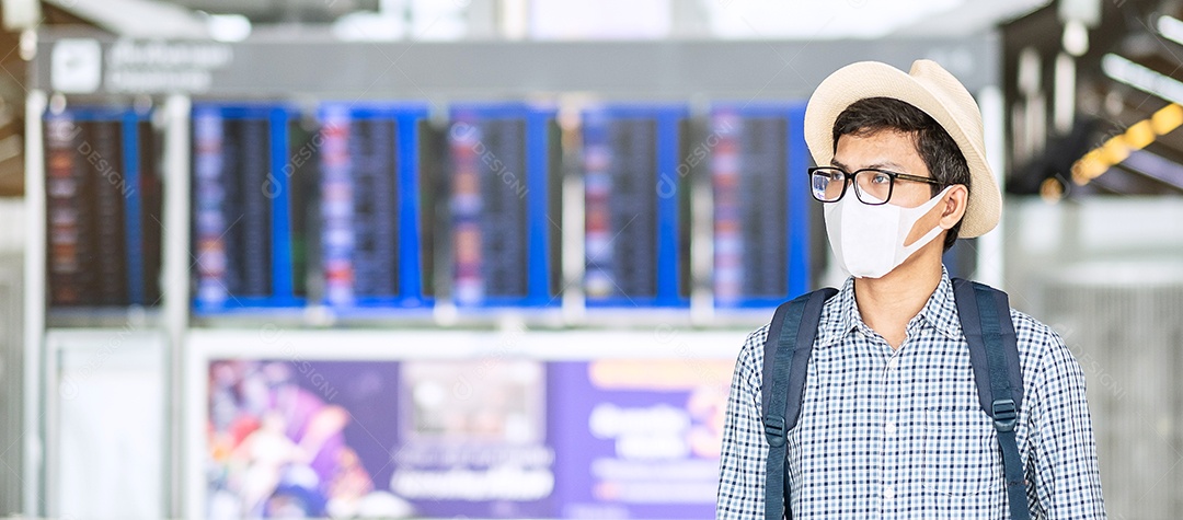 Homem adulto jovem usando máscara facial no terminal do aeroporto