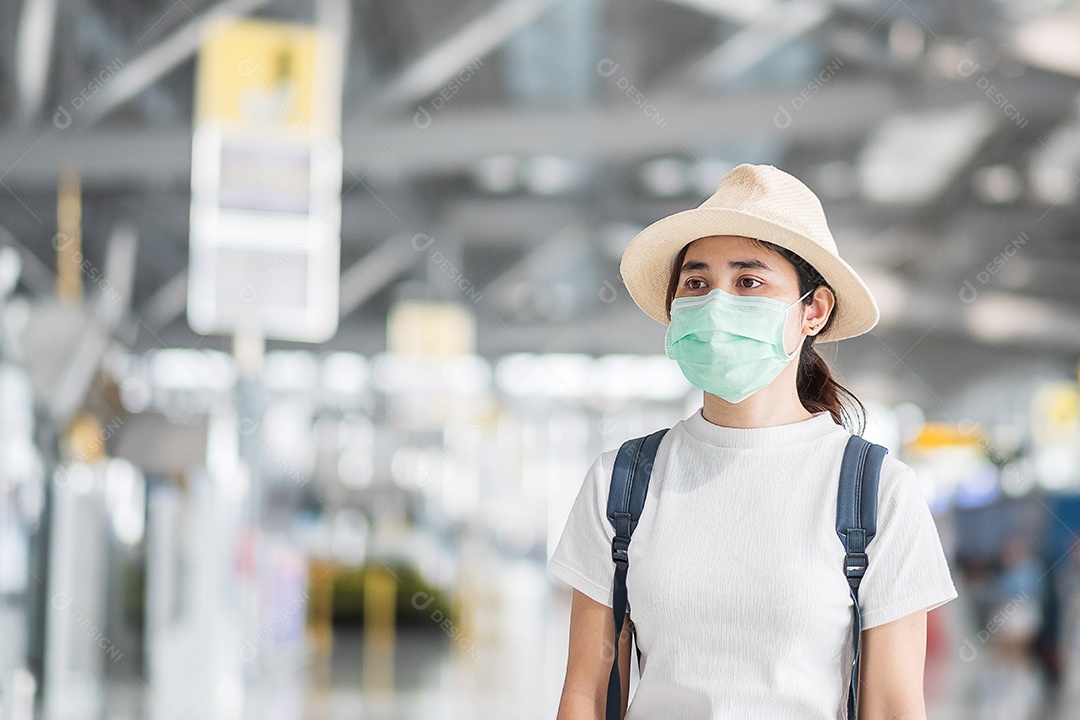 Mulher adulta jovem usando máscara cirúrgica no terminal do aeroporto