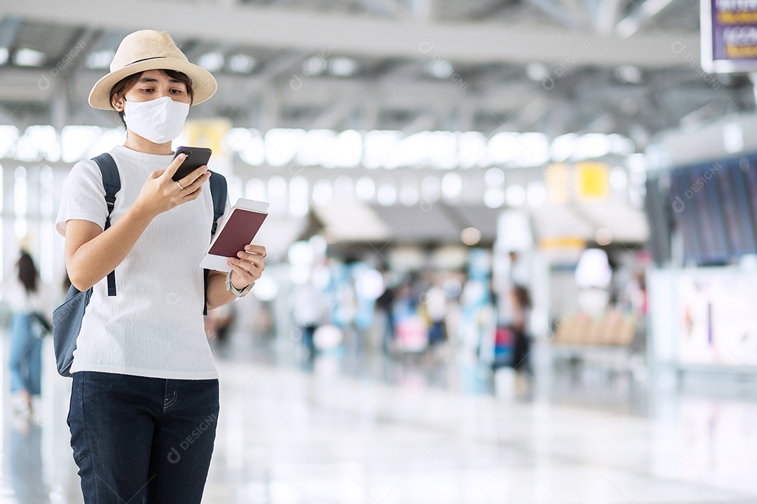 Mulher adulta jovem com máscara facial segurando passaporte no aeroporto