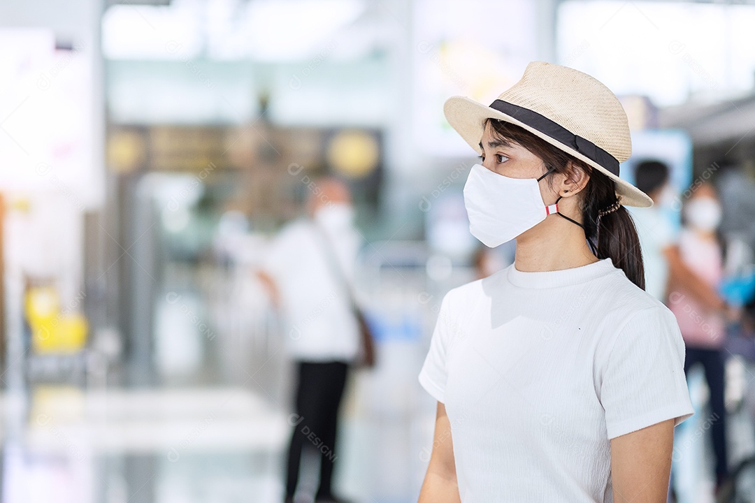 Mulher adulta jovem usando máscara facial no terminal do aeroporto