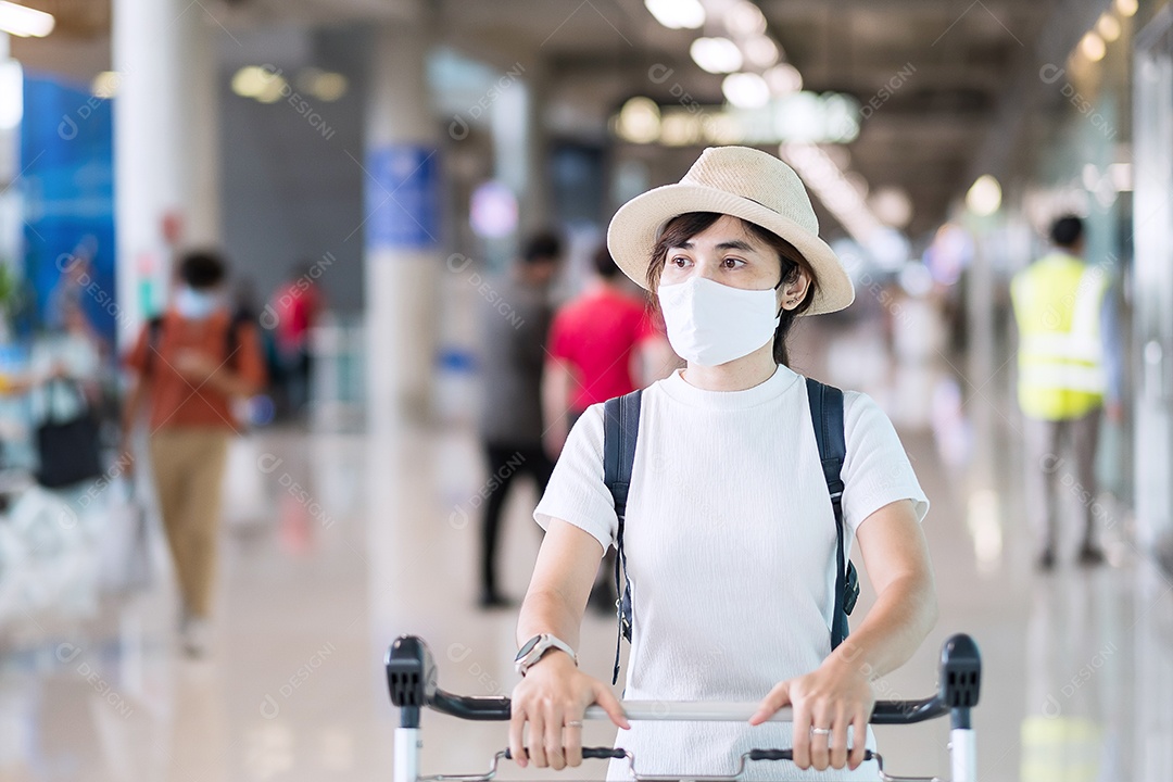 Mulher adulta jovem usando máscara facial no terminal do aeroporto