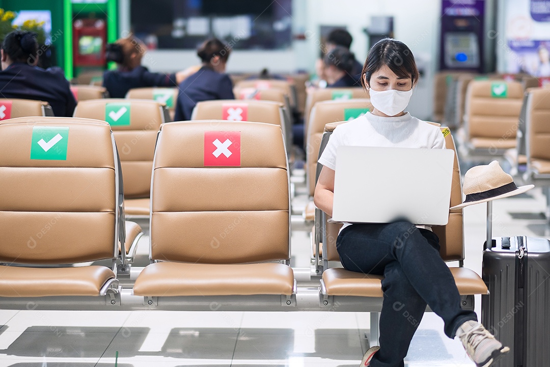 Jovem mulher usando máscara facial e usando computador laptop