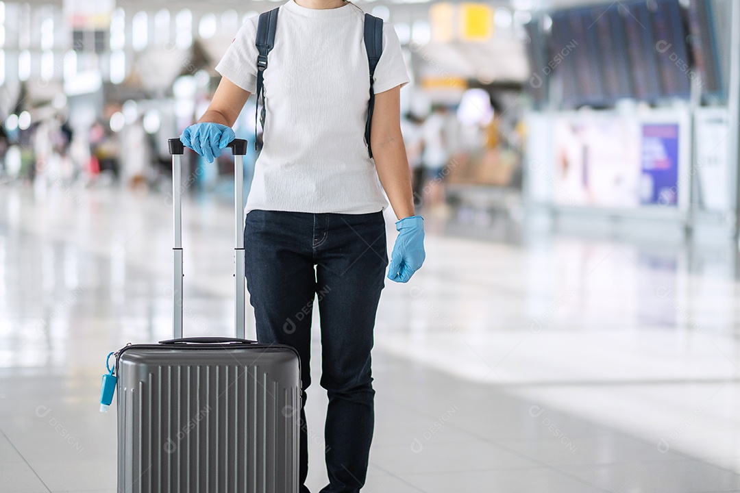 Viajante jovem usando luva de nitrilo segurando a alça de bagagem