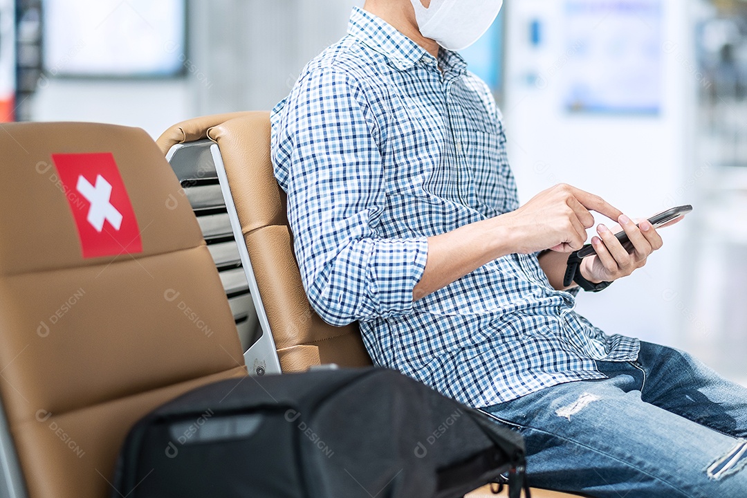 Jovem macho usando máscara facial e usando smartphone móvel