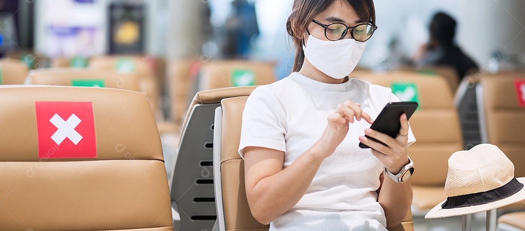 Jovem mulher usando máscara facial e usando smartphone móvel