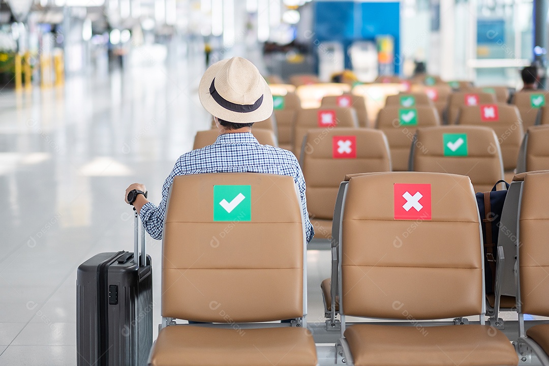 Jovem homem usa máscara facial sentado na cadeira no terminal do aeroporto,