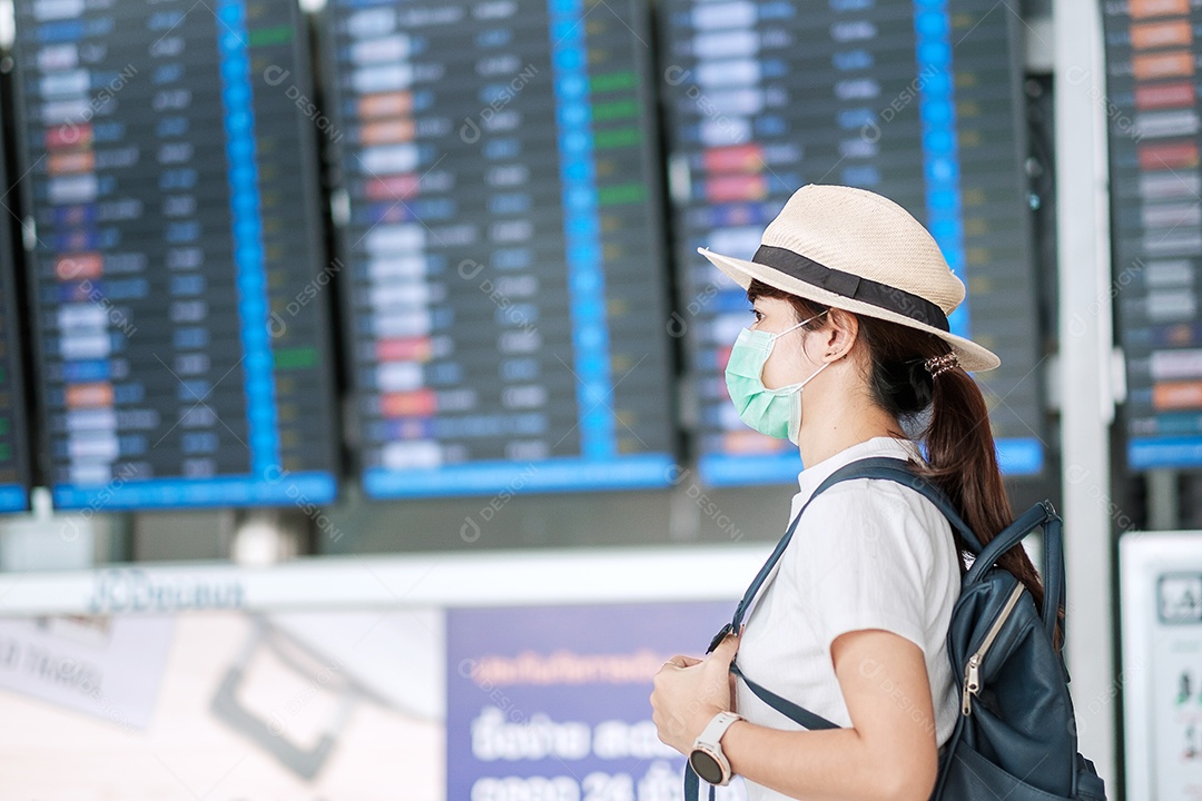 Mulher adulta jovem usando máscara cirúrgica no terminal do aeroporto