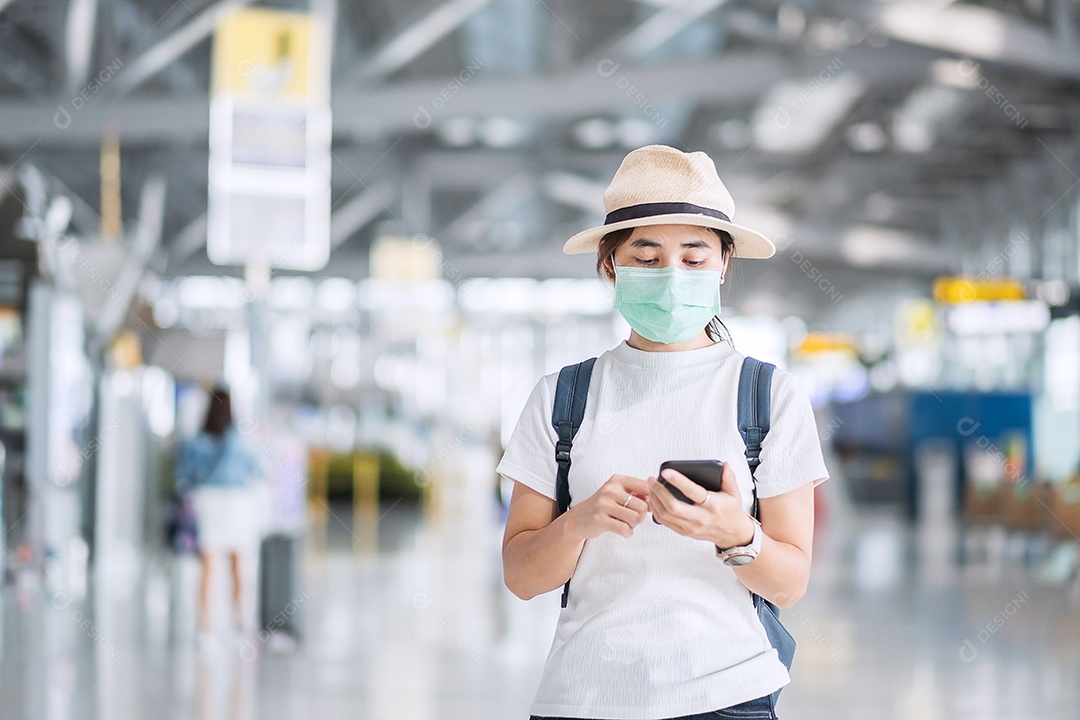 Jovem mulher usando máscara facial e usando smartphone móvel