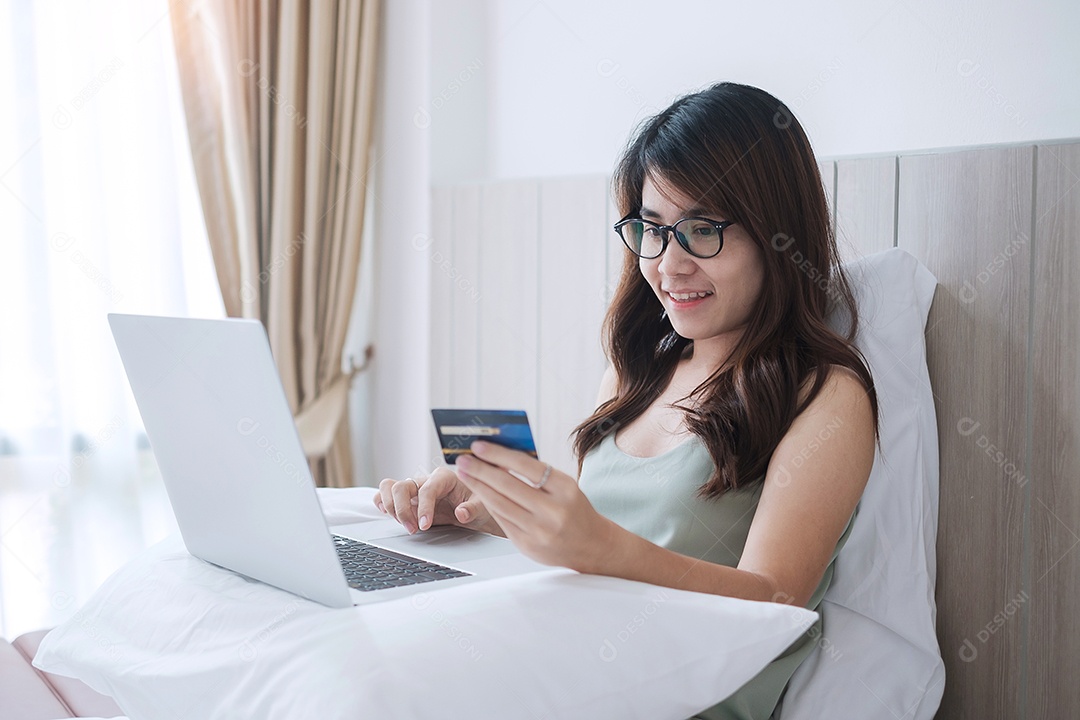 Mulher feliz segurando cartão de crédito e usando computador portátil