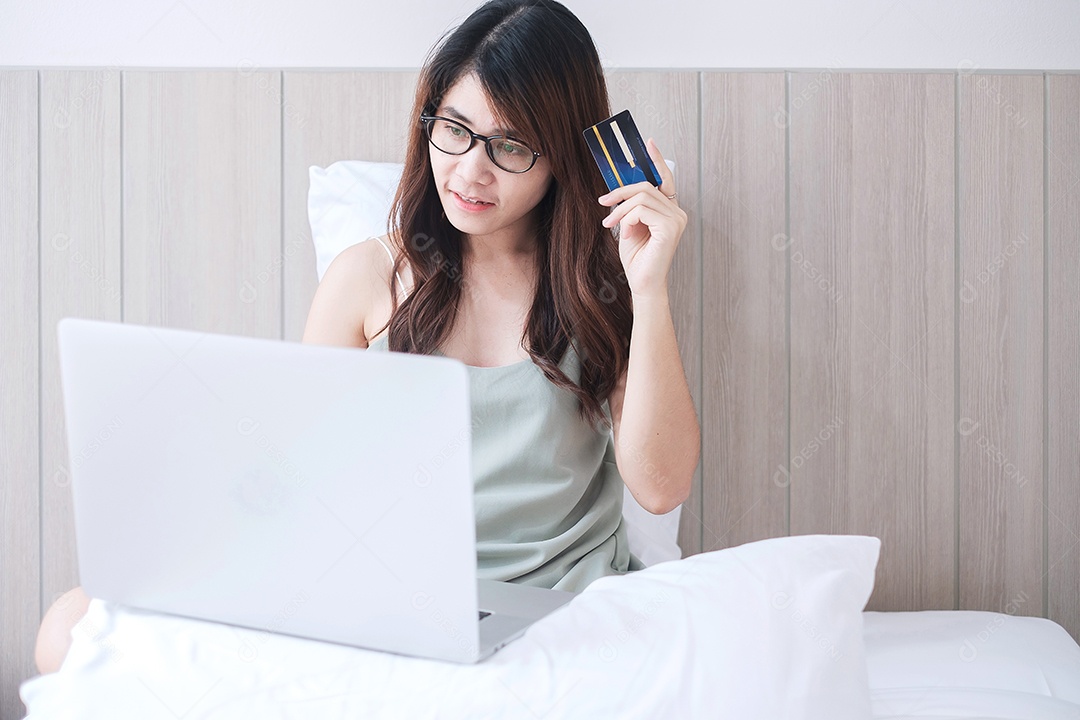 Mulher feliz segurando cartão de crédito e usando computador portátil