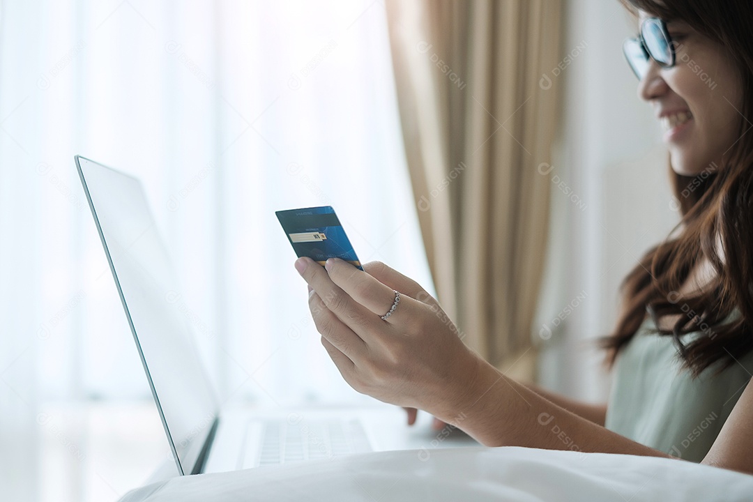 Mulher feliz segurando cartão de crédito e usando computador portátil