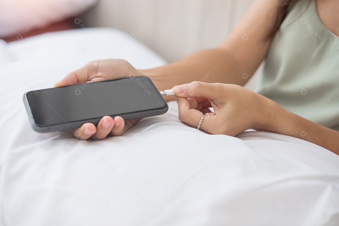 Mãos de mulher carregando bateria no celular inteligente no quarto