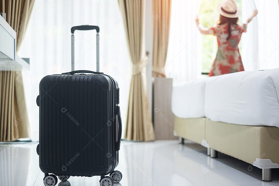 Bagagem no quarto de hotel moderno com fêmea adulta jovem feliz relaxa