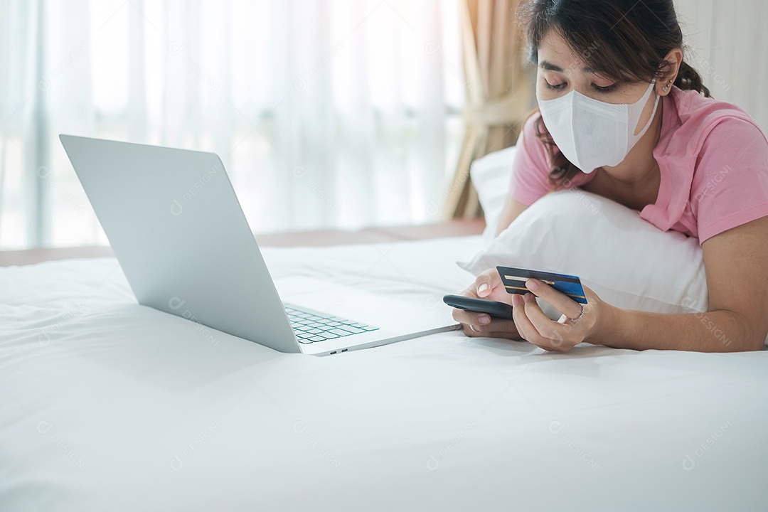 Mulher doente com máscara facial segurando cartão de crédito e usando compra